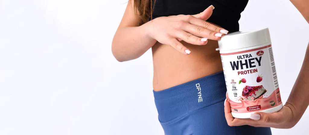 Ženski model drži Olympic Ultra Whey protein za mršavljenje cizkejk malina